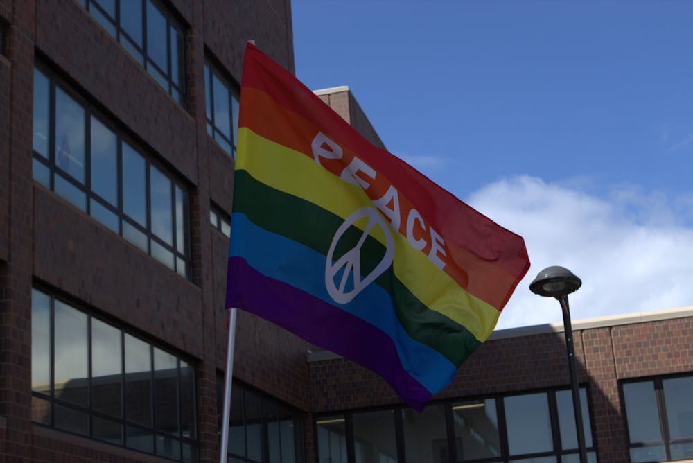 <p>A student displays a “Peace” flag during a campus Gay Pride Parade in April 2019.</p>