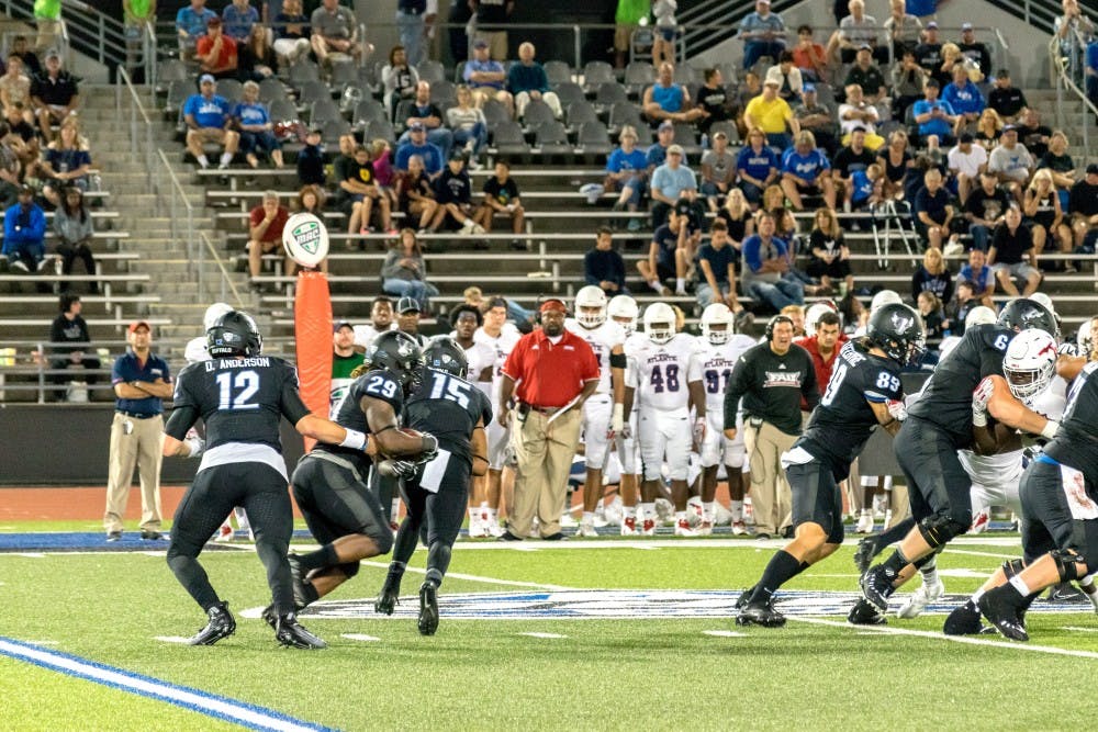 <p>Junior quarterback Drew Anderson hands off the ball to redshirt sophomore running back Emmanuel Reed. Reed ran for 144 yards and three touchdowns Saturday.</p>