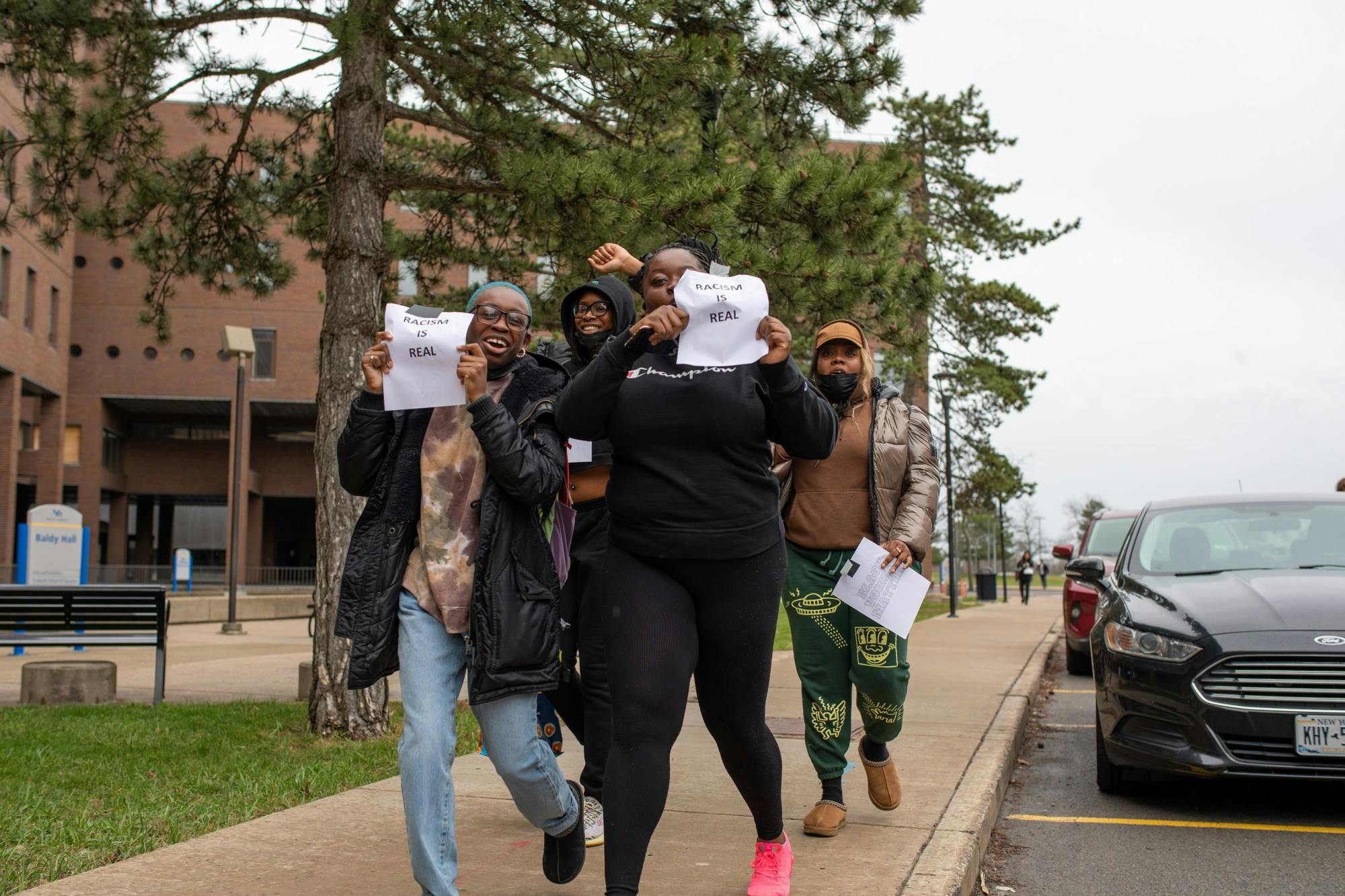 Students hold up signs reading “Racism is real” during a protest of Lt. Col Allen West’s speech Thursday.