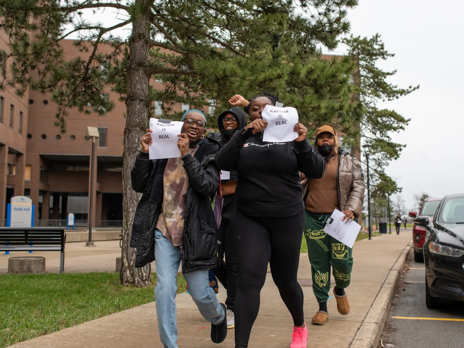 Students hold up signs reading “Racism is real” during a protest of Lt. Col Allen West’s speech Thursday.