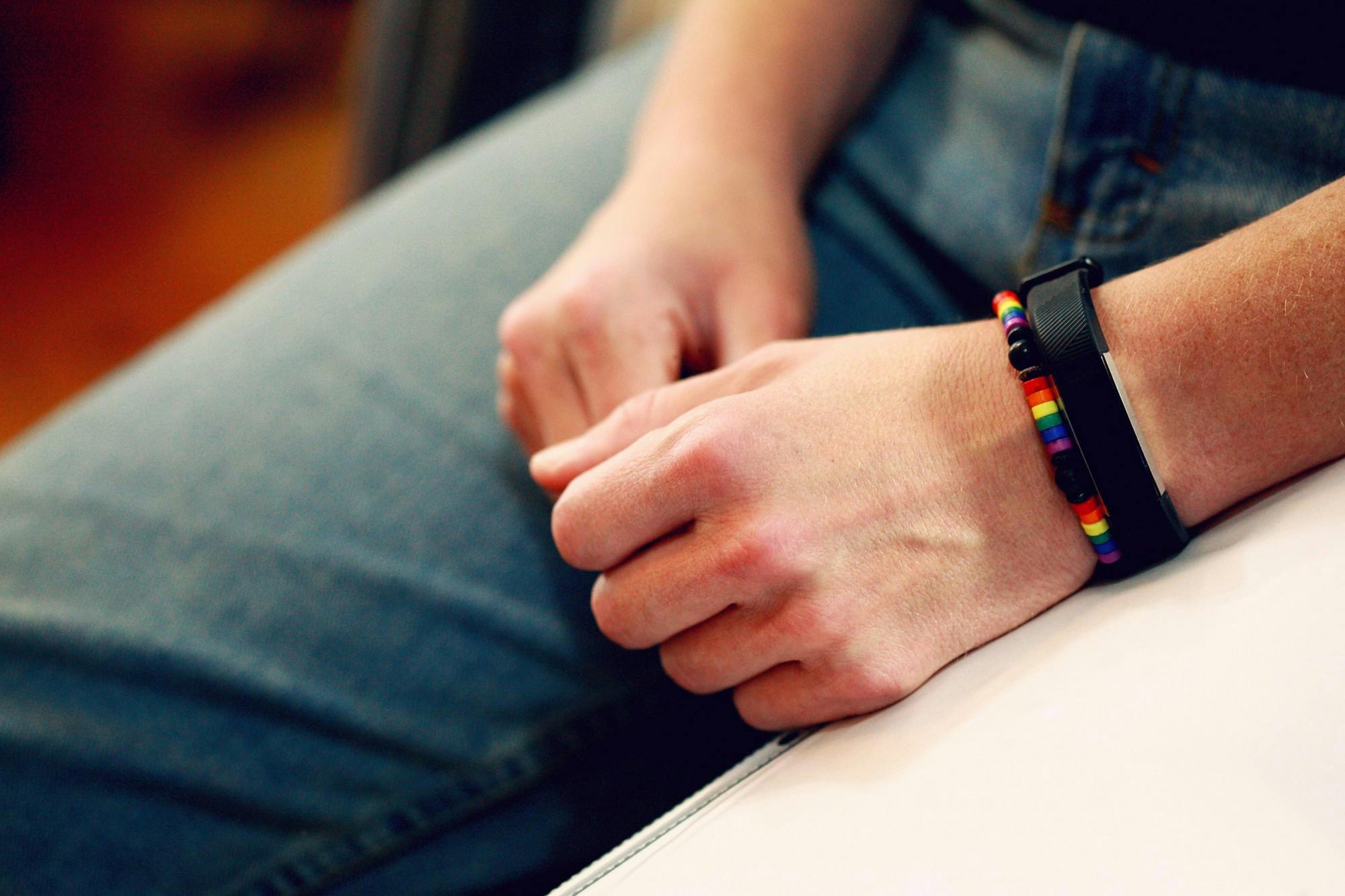 A person wears a bracelet and a FitBit on their left hand.