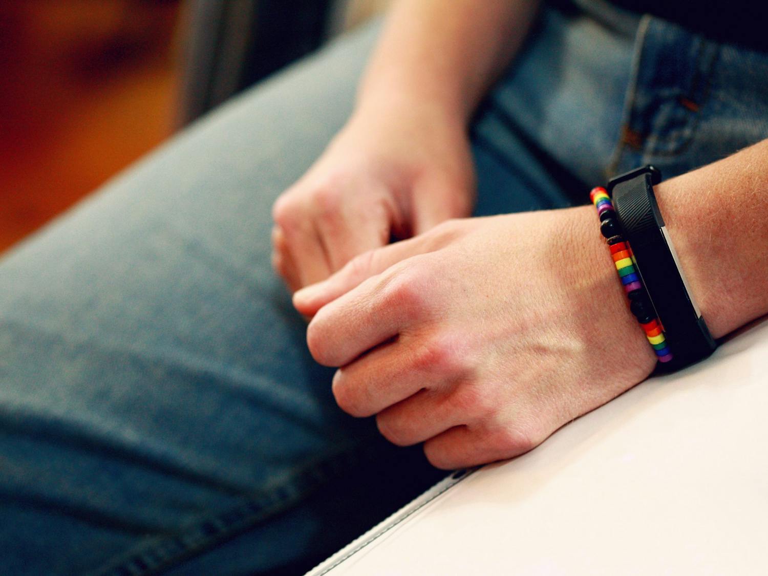 A person wears a bracelet and a FitBit on their left hand.