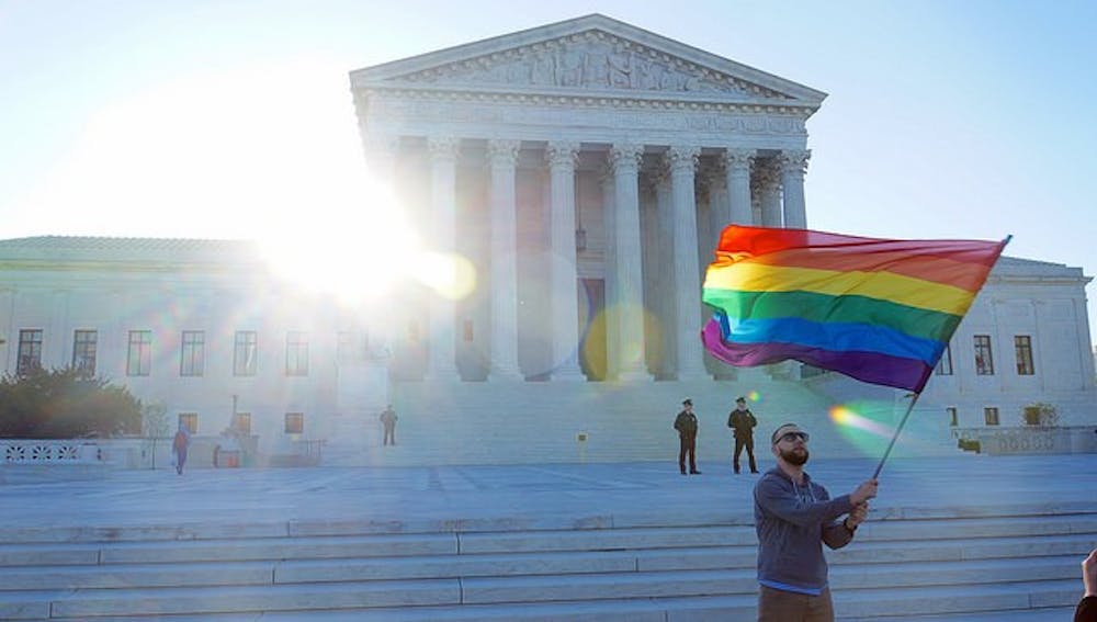 <p>A same-sex marriage supporter waves a gay pride flag outside the Supreme Court, which ruled on June 26 that all states must perform same-sex marriages and recognize same-sex marriages performed in other states. </p>