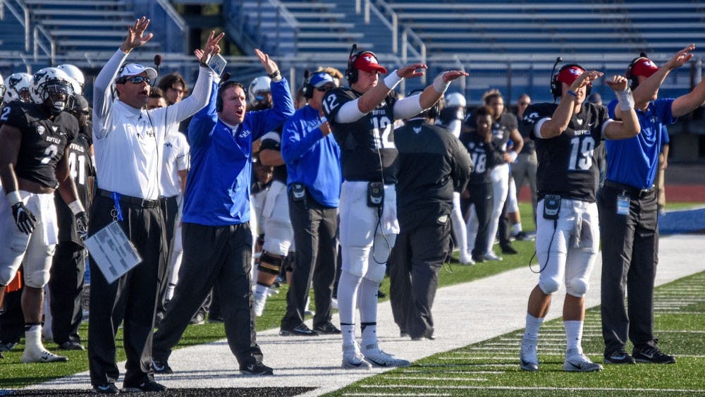 <p>UB football coaches and players stand on the sideline.&nbsp;UB football was blown out Saturday by Northern Illinois and are 0-3 in the MAC this season.</p>