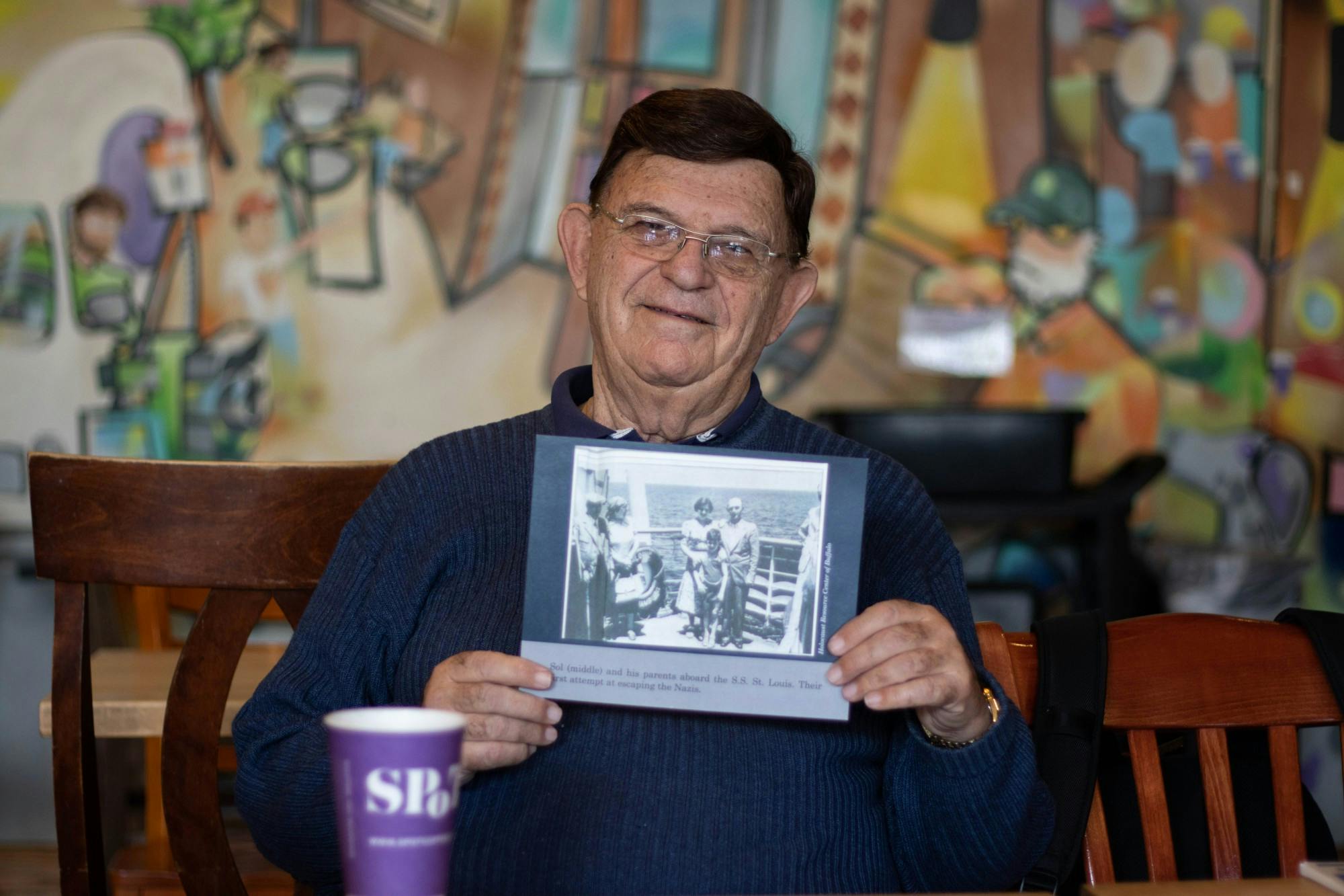 Sol Messinger holds up a photo of him and his family on a ship to Cuba. 