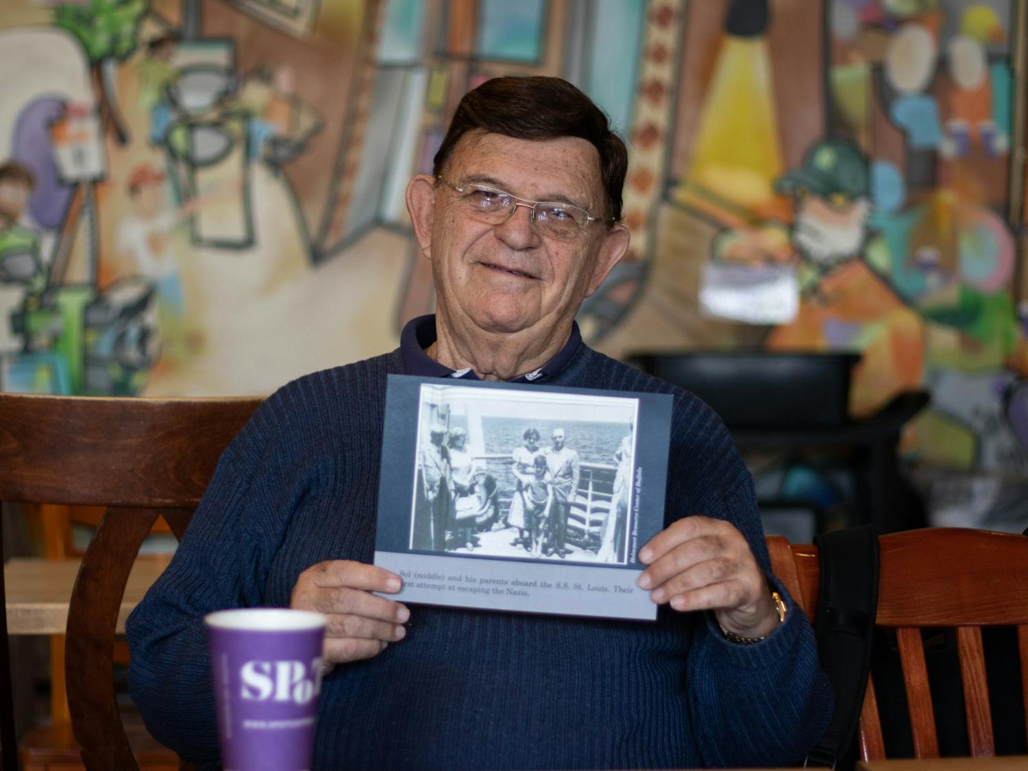 Sol Messinger holds up a photo of him and his family on a ship to Cuba. 