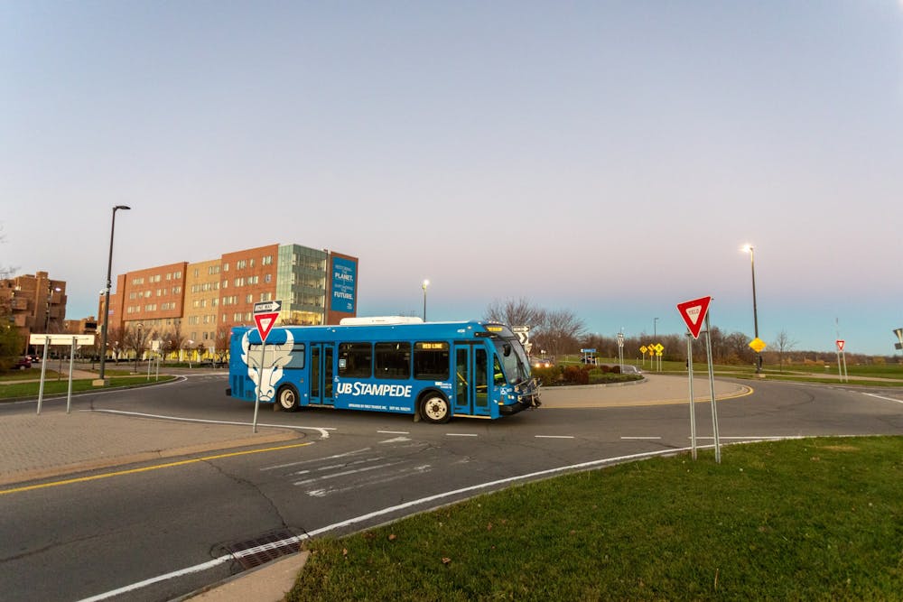 <p>A Stampede bus drives through the roundabout in front of Greiner Hall.</p>