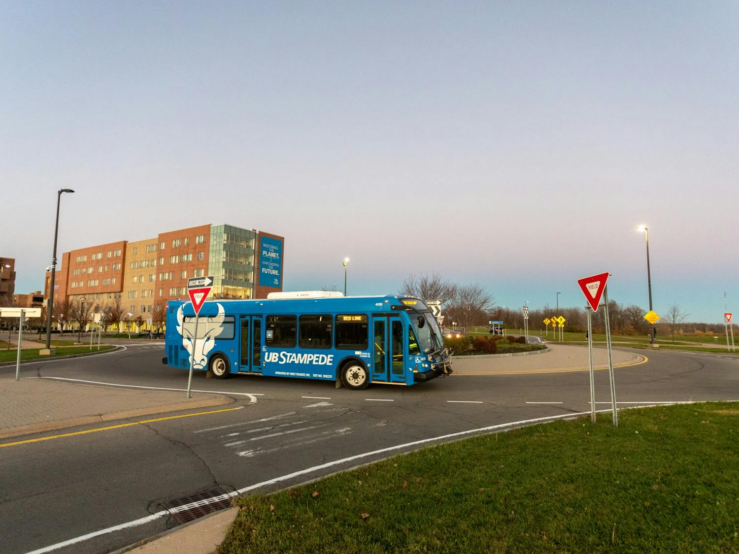 A Stampede bus drives through the roundabout in front of Greiner Hall.