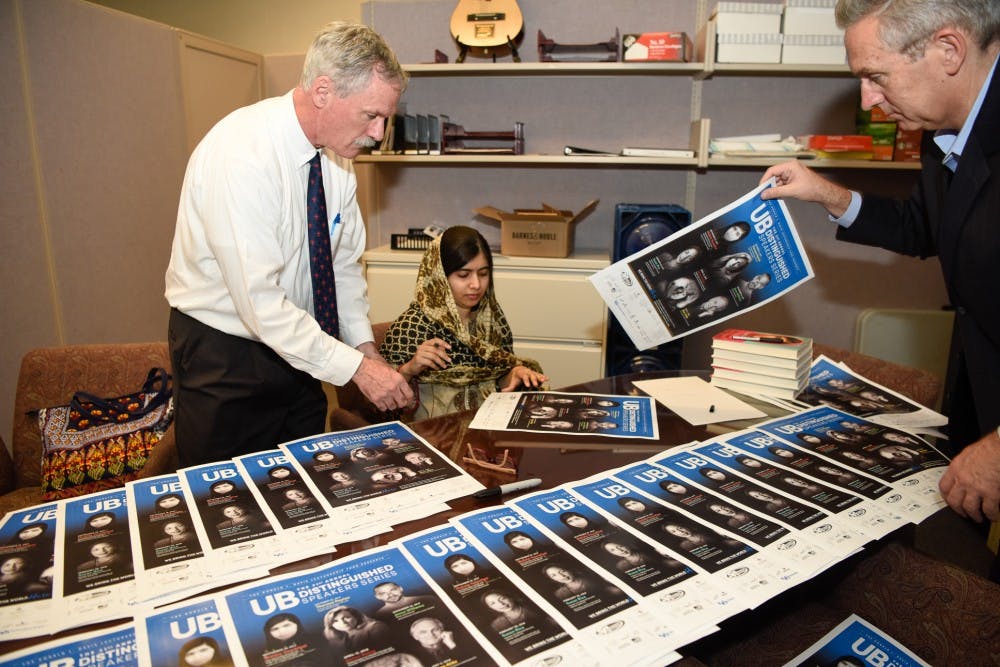 <p>William Regan (left) hands Distinguished Speakers Series posters to Nobel Peace Prize winner and activist Malala Yousafzai. Regan’s office, the office of University Events, has hosted the lecture-based, educative series for over three decades at UB.</p>