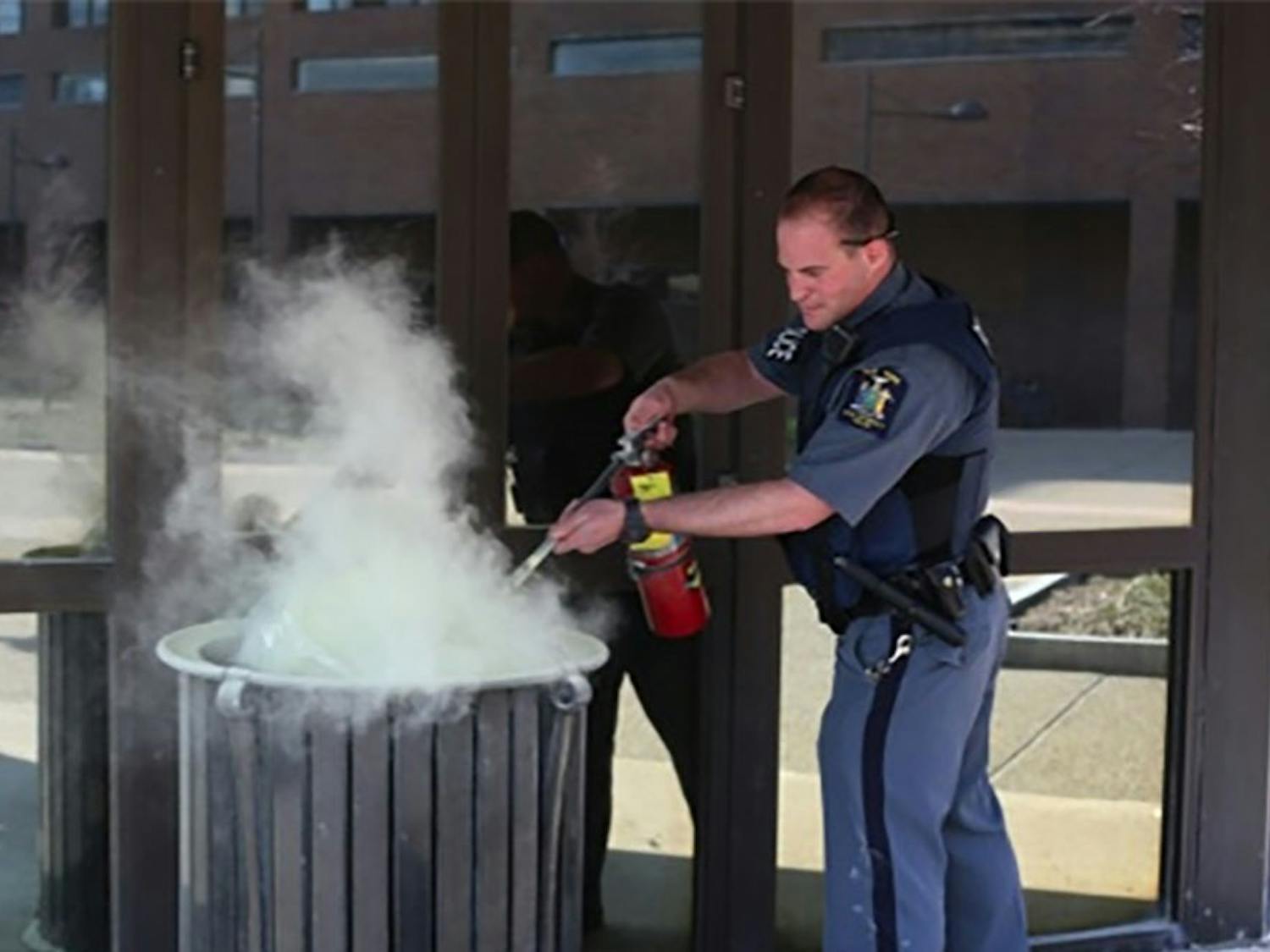 UPD Officer David Stall uses a fire extinguisher to put out a garbage can fire outside the Student Union on April 17. Assistant Chief of Police Chris Bartolomei recently attended a three-day training targeted to fight against implicit bias in policing.
