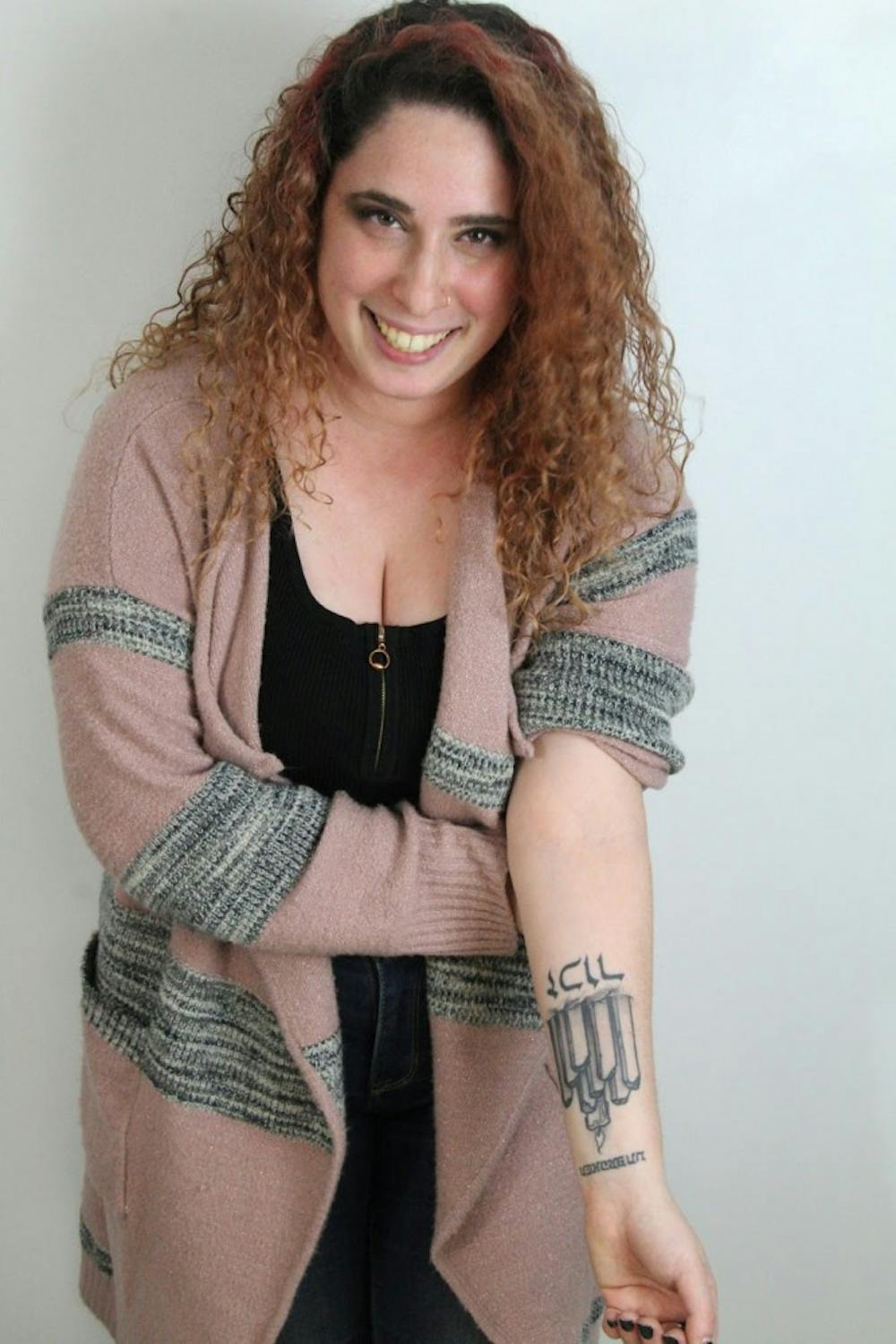 <p>Sarah Bienstock, UB psychology major, photographed with two of her tattoos. The columns represent the lives of Jewish children cut short in the Holocaust and underneath is the Hebrew word “Zachor” or “remember.”</p>