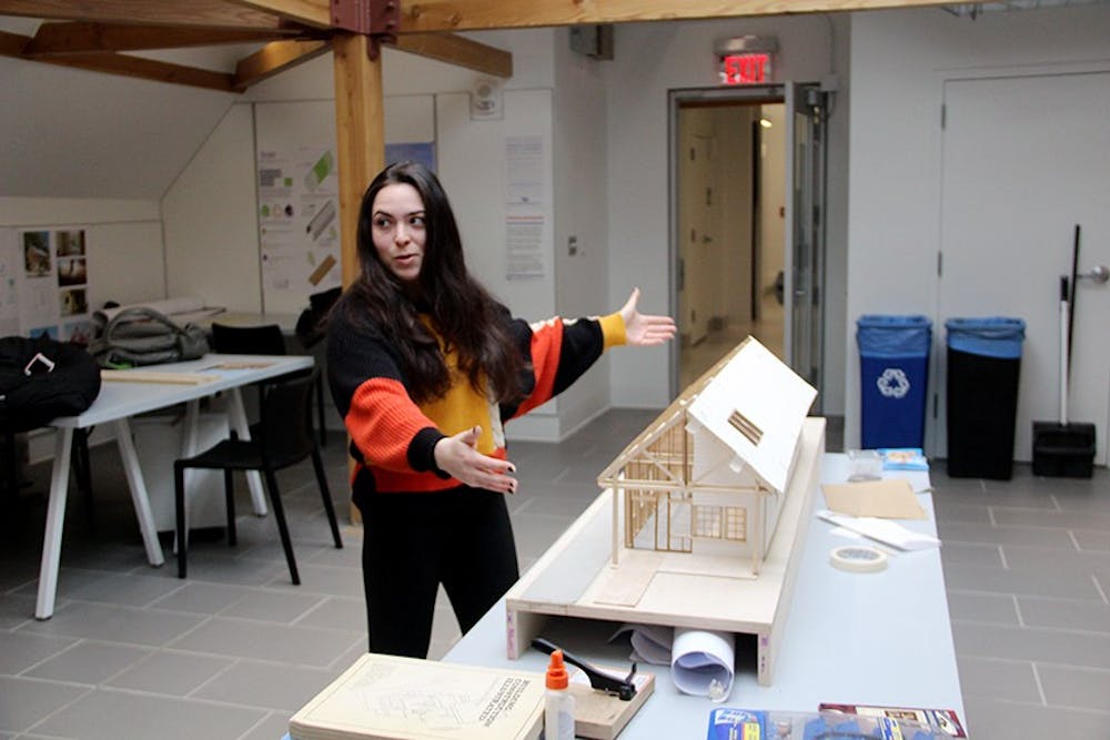 <p>Graduate student Alexa Russo stands in front of a model constructed from her affordable housing design. Russo designed the one-story row-house as a model for students to eventually build a home for a Buffalo family.</p>