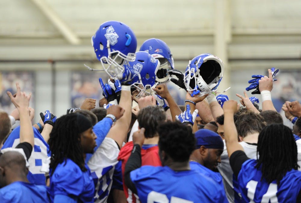 <p>Members of the football team raise their helmets at the conclusion of the first day of spring practice. Senior Punter Tyler Grassman won Mid-American Conference Special Teams Player of the Week. </p>