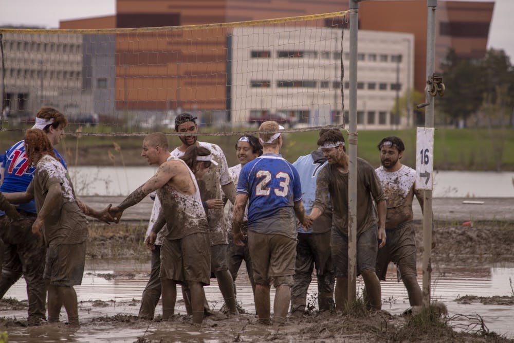 Students shake hands following a spirited game of mud volleyball during Oozefest 2019.
