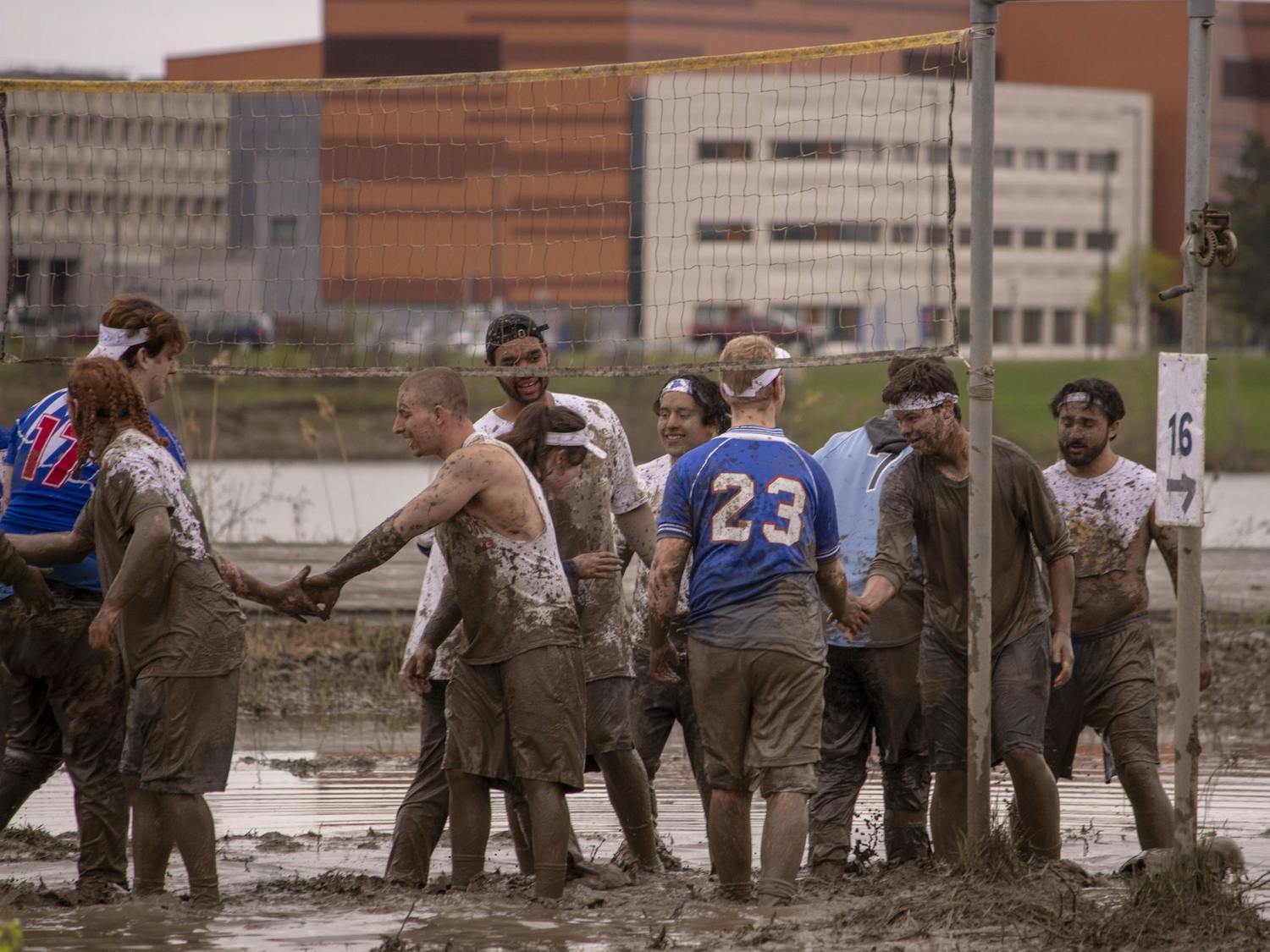 Students shake hands following a spirited game of mud volleyball during Oozefest 2019.