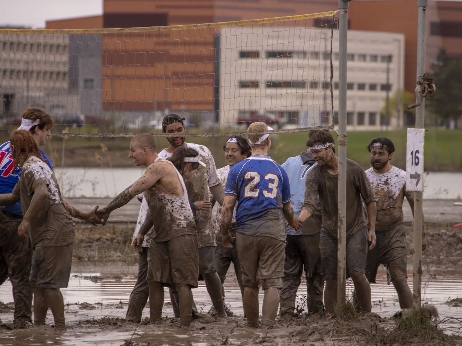 Students shake hands following a spirited game of mud volleyball during Oozefest 2019.