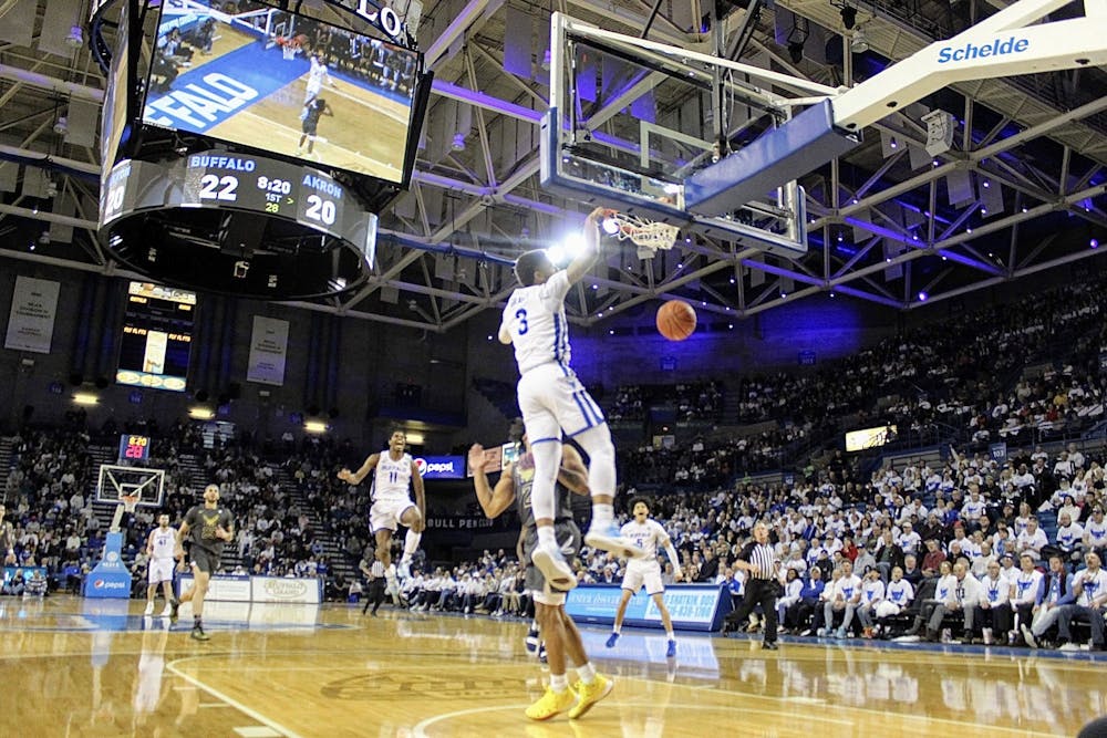 <p>Junior guard Jayvon Graves dunking the basketball after a steal while teammates, sophomore forward Jeenathan Williams and freshman guard Savion Gallion jump with excitement.</p>