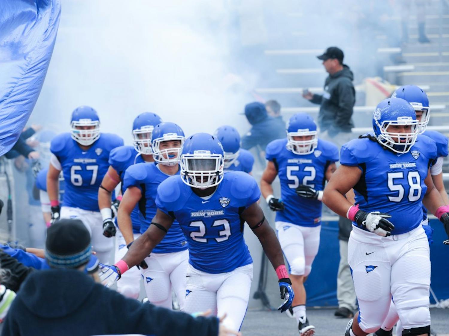 The UB football team runs out of the tunnel of the UB Stadium. The gap between the schools in the Power Five conferences and Mid-Majors like UB seems to be widening, raising the question if it is worth is for schools to have Division I football teams outside of the Power Five.