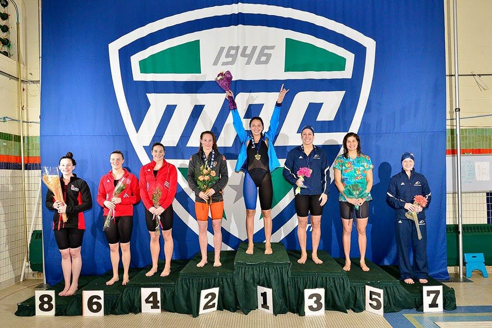 <p>Megan Burns stands with her hands raised in celebration after winning the 100-meter relay at the swimming and diving MAC Championships last February. The victory was part of a perfect 52-0 season for the freshman.</p>