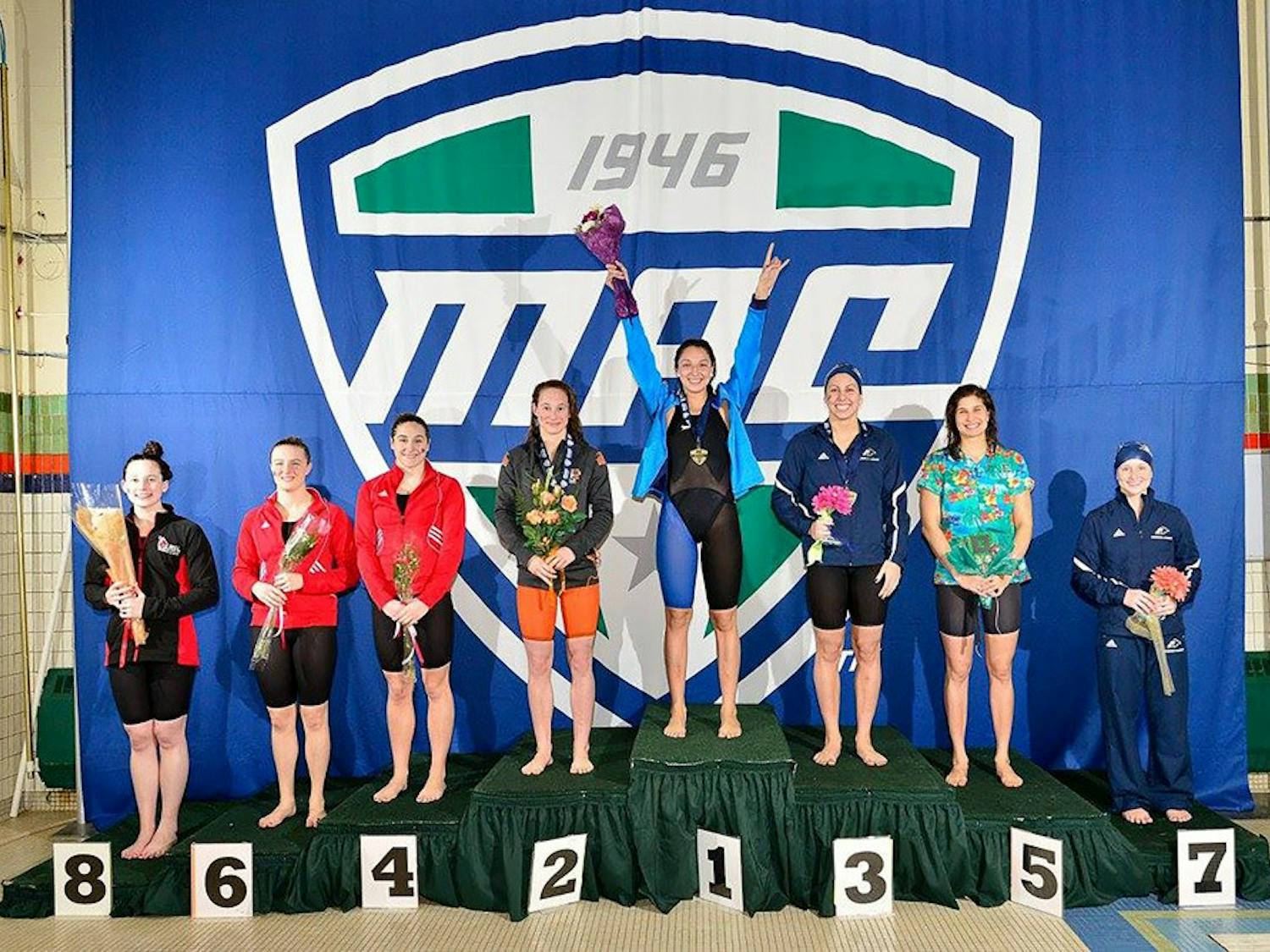 Megan Burns stands with her hands raised in celebration after winning the 100-meter relay at the swimming and diving MAC Championships last February. The victory was part of a perfect 52-0 season for the freshman.