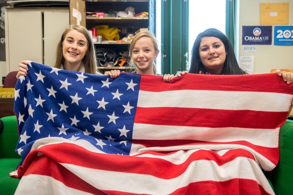 <p>(From left to right)&nbsp;Katie Henshaw, a senior psychology major, Erica Lutz, vice president of UB College Republicans and a junior communication and political science major, and Alexis Ogra, president of UB College Republicans and a sophomore history major, pose with the American flag in the club office.</p>