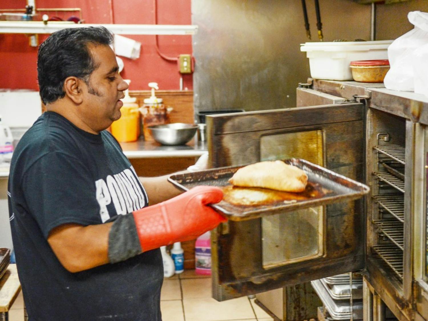 MD B Ali, owner of Calios, takes a calzone out of the oven at the Main Street location. Calios provides those looking for food around South Campus with a variety of calzones, including dessert-style.