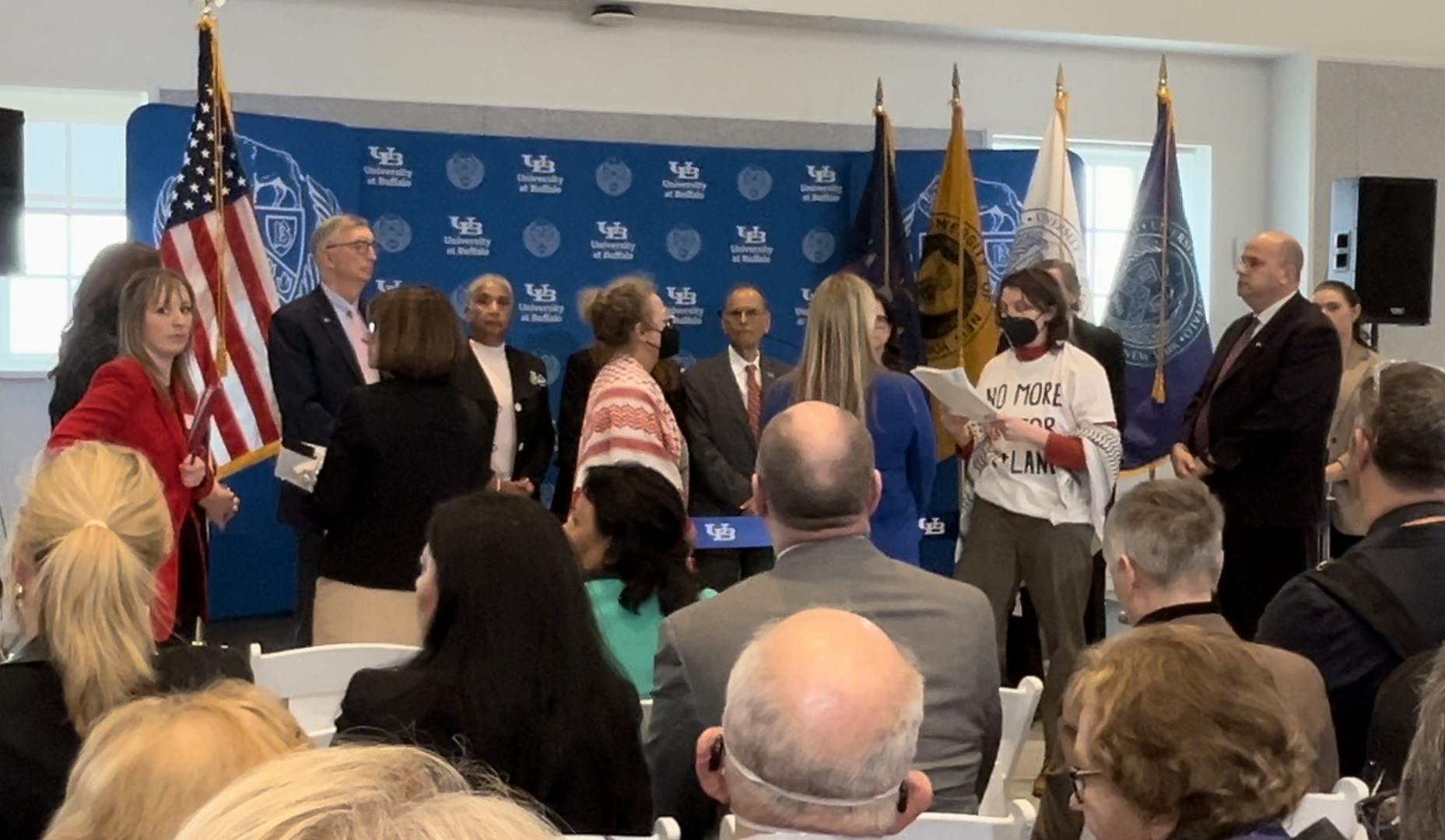 Officials and speakers listen while a SUNY BDS protester reads a letter directed at UB President Satish Tripathi.