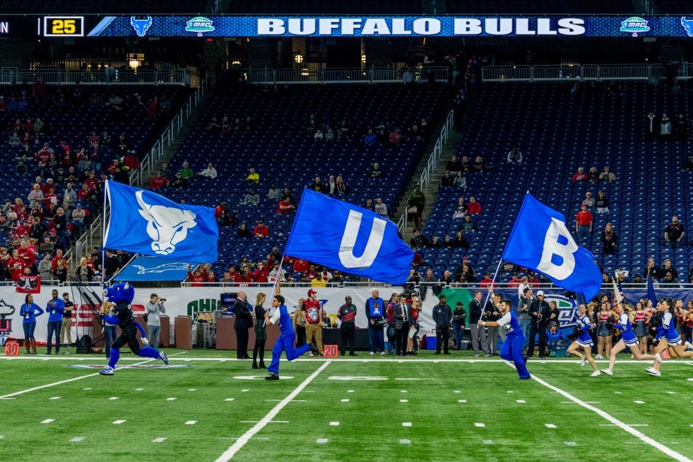 <p>Victor E. Bull and members of the cheerleading team lead the Bulls onto the field at the MAC Championship game. Buffalo was selected to play in the Dollar General Bowl.</p>