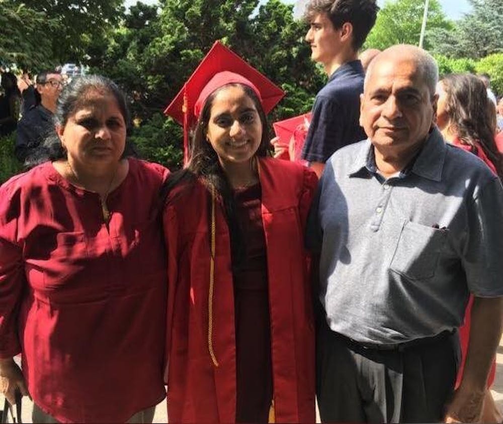 <p>Minnoli Aya (center) with her mother Madhvi and her father at her high school graduation.</p>