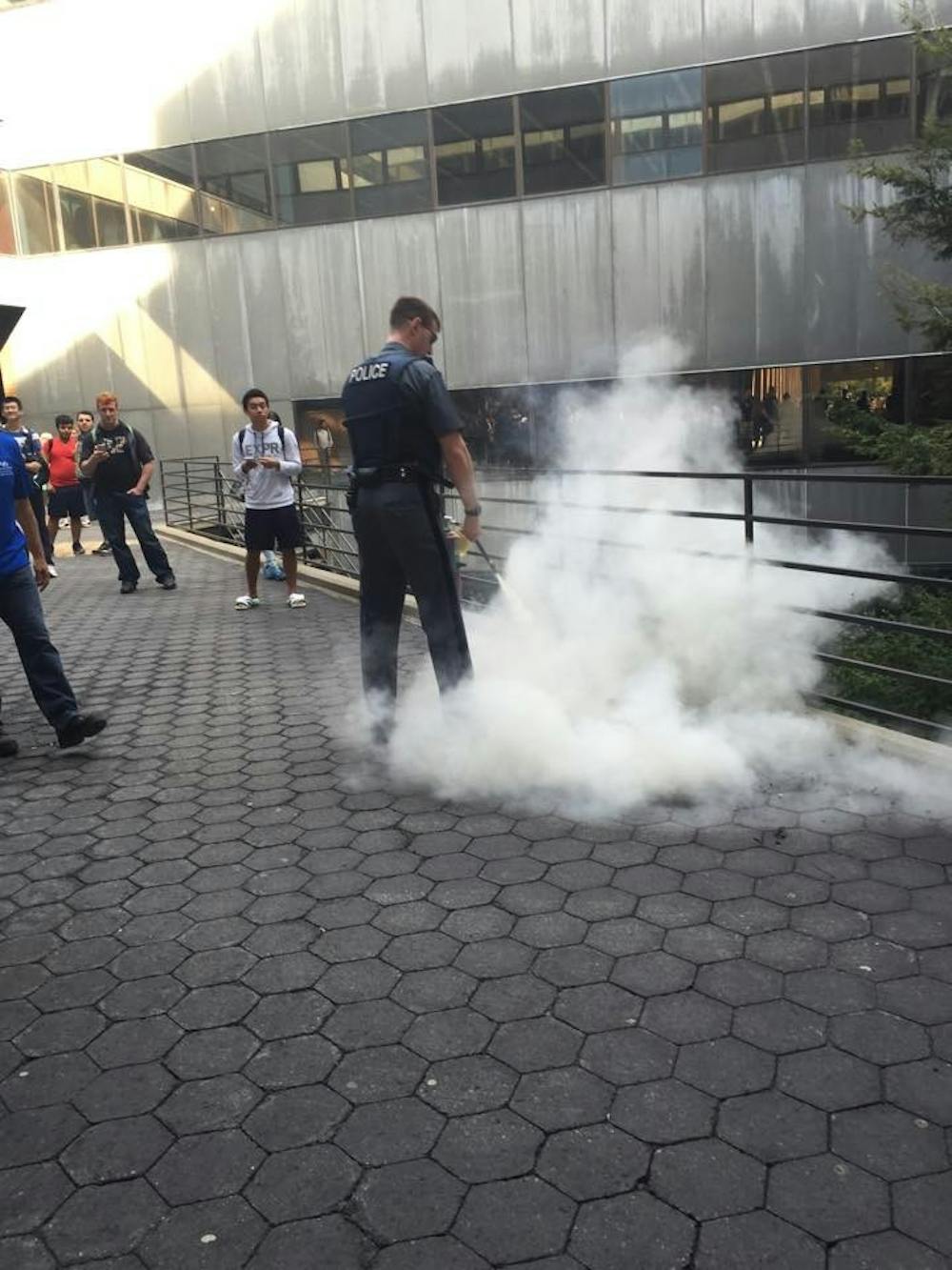 <p>UPD Officer Jeffrey Walters puts out the small fire with an extinguisher outside of Lockwood Friday. </p>