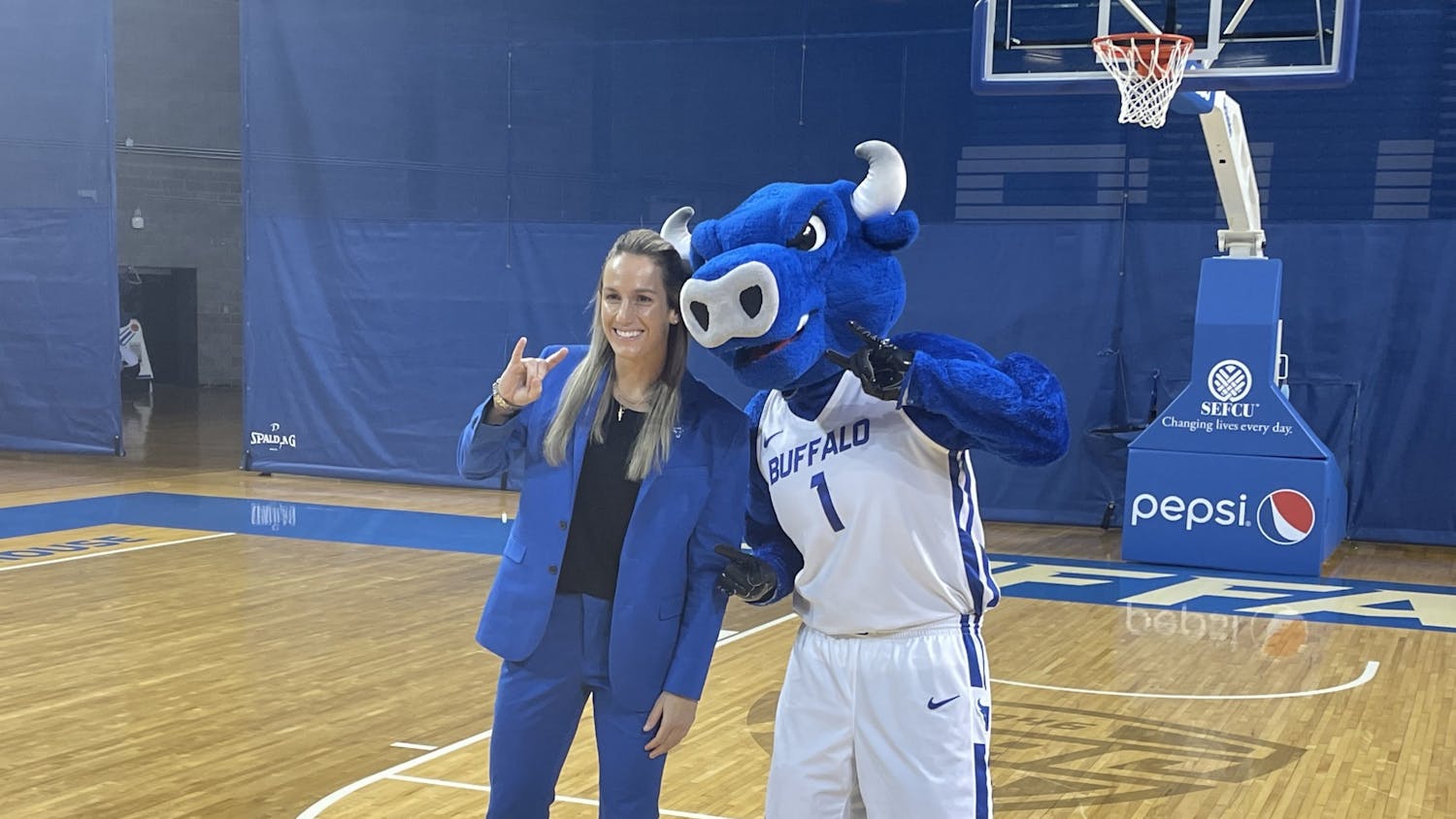 Women’s basketball head coach Becky Burke poses for a photo with Victor E. Bull.