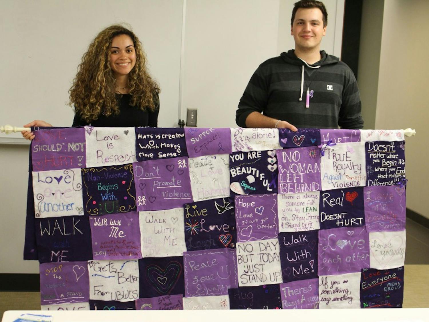 Stephanie Vazquez (left) and Jamie Core (right) hold a quilt made by UB students and faculty to raise awareness on sexual violence as part of the annual Take Back the Night event. 