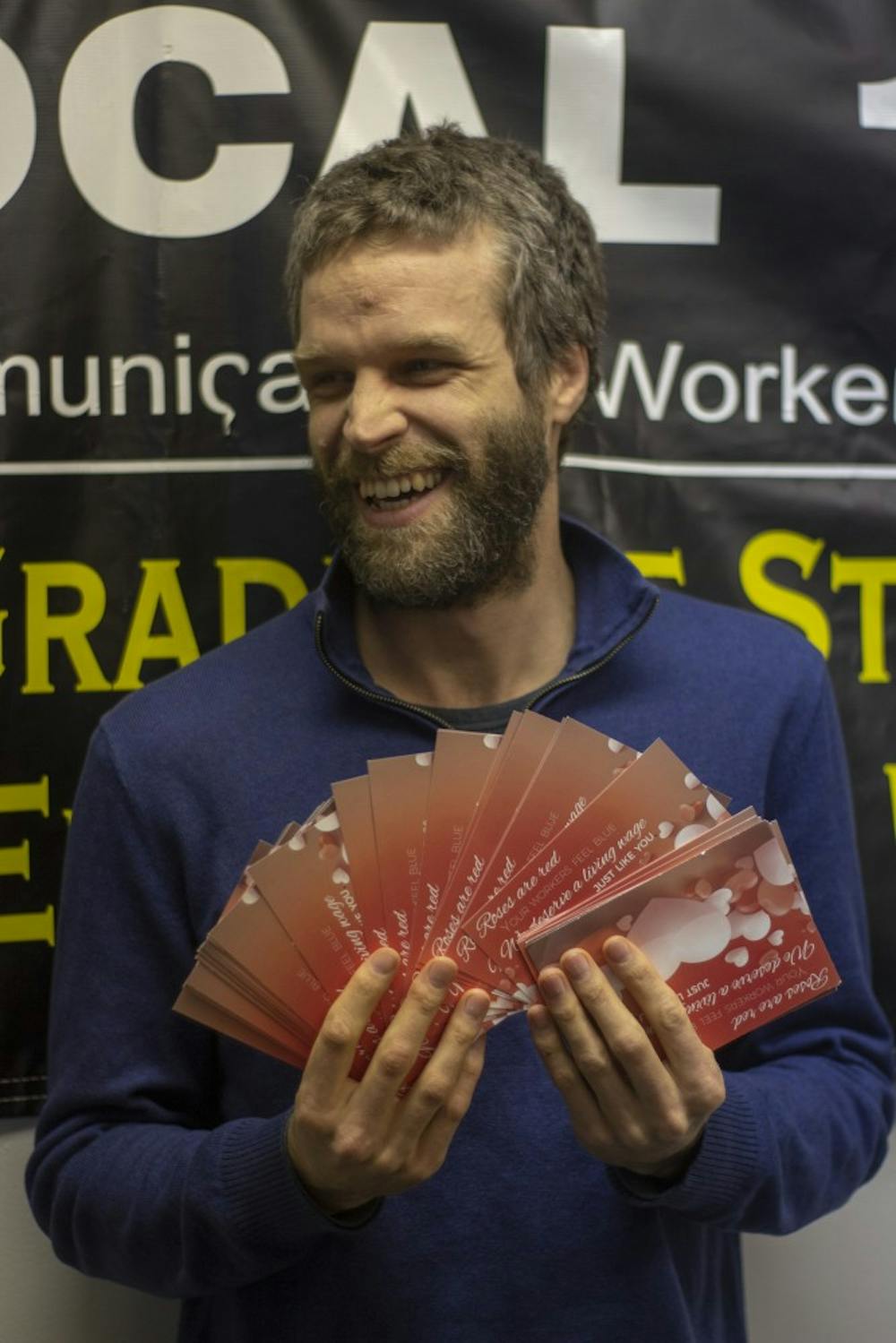 <p>Ph.D. student Willis McCumber holds up Valentine’s Day cards from fellow graduate TAs. Willis, along with other “mobilizers,” will send the cards to President Tripathi’s home address.&nbsp;</p>
