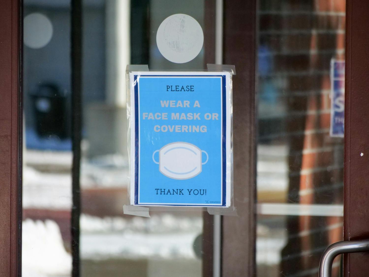 A sign on the door to the Student Union asks visitors to wear a mask when walking around campus.