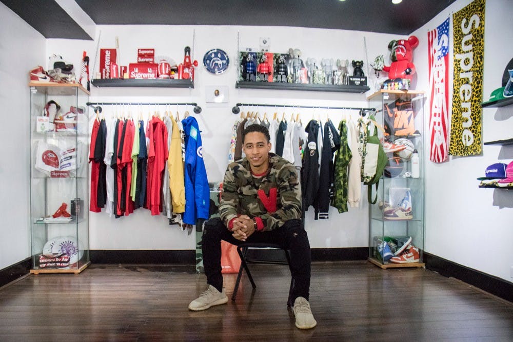 <p>Yusef Burgos sits in his new clothing store The Cellar on Elmwood Avenue. The store features high-end clothing and shoes from brands like Bape, Supreme, Nike and Adidas.</p>