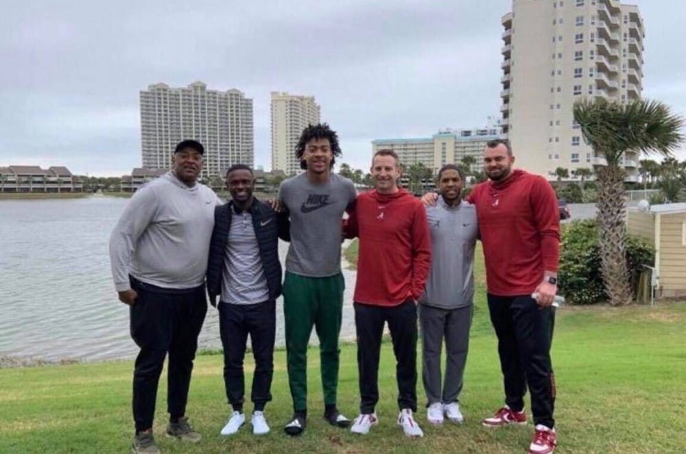 Former assistant head coach Bryan Hodgson stands with Nate Oats and a recruit in Alabama gear.