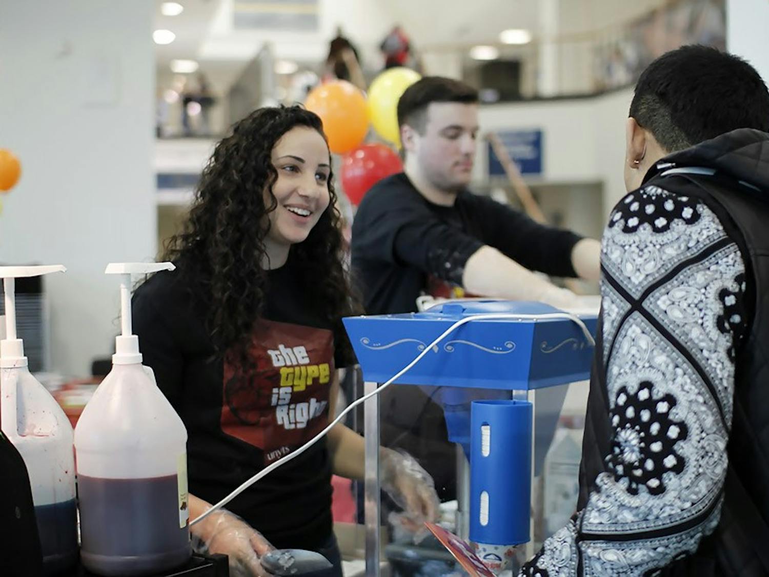 Carly Kreitzberg (front), a senior communication and psychology major, and James Roy (back), a senior communication major, serve snow cones and cotton candy to students as part of the "Type is Right" event aims to get more students to become organ donors.