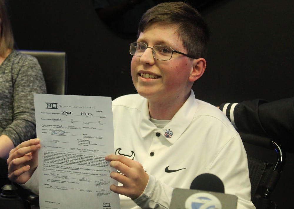 <p>Sixteen-year old Peyton Longo holds up his National Letter of Intent after signing on as a member of the Bulls. Longo suffers from a form of muscular dystrophy and has joined the team through Team IMPACT.</p>