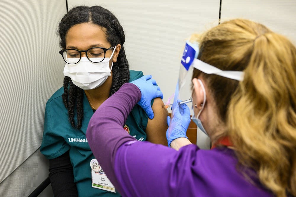 Nurse Nicole Metko, right, vaccinates Eden Charles, a researcher in the School of Medicine.