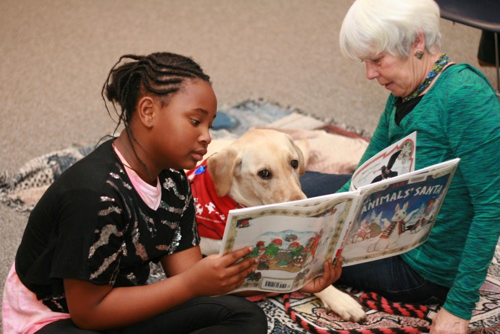 An Odyssey Junior student reads alongside program staff.