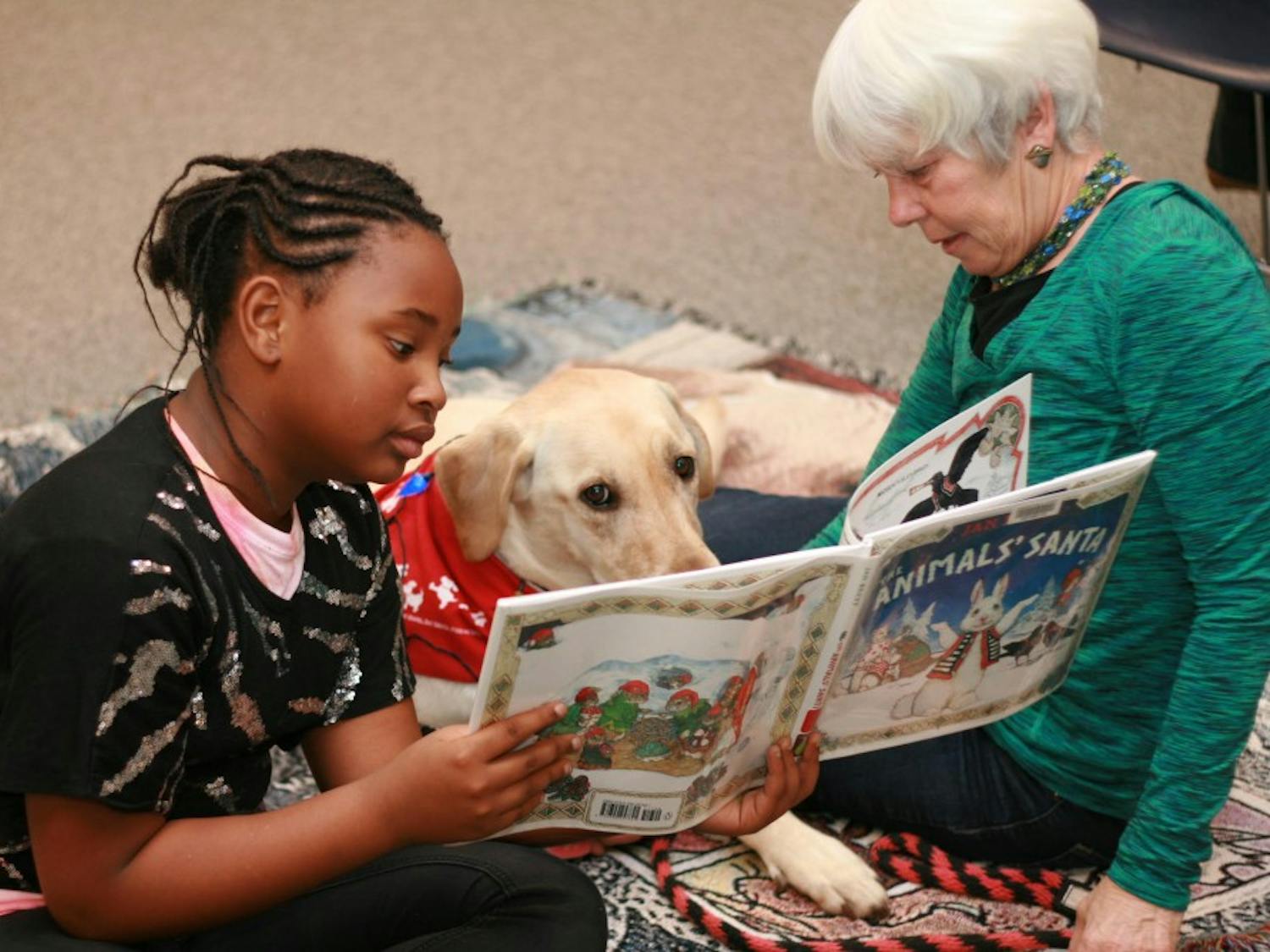 An Odyssey Junior student reads alongside program staff.