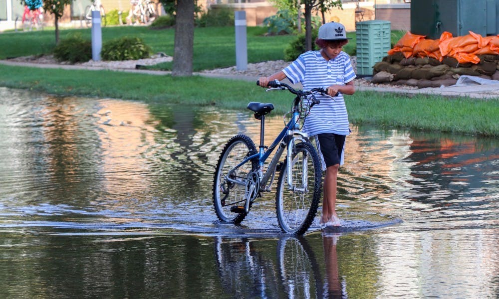 Boy walks his bike through flooding on the Madison Isthmus