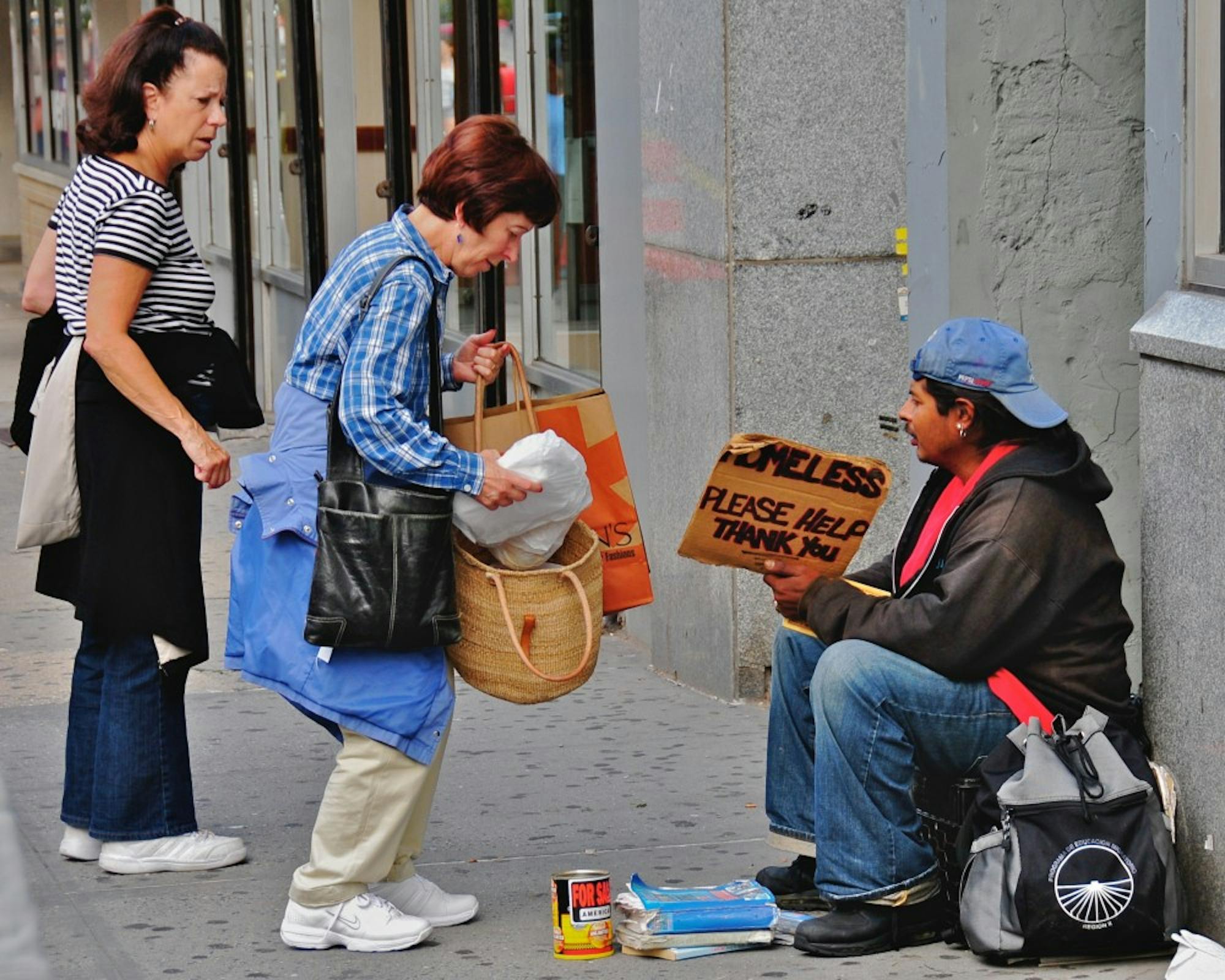 This was taken about halfway up the block on the east side of Broadway, between 79th and 80th Street. It's at the north end of the "Filene's Basement" store on the corner, and it's a place where I've often seen homeless people holding up a sign that asks for assistance...

With very rare exceptions, I haven't photographed these homeless people; it seems to me that they're in a very defensive situation, and I don't want to take advantage of their situation. But something unusual was happening here: the two women (who were actually cooperating, and acting in tandem, despite the rather negative demeanor of the woman on the left) were giving several parcels of food to the young homeless man on the right.

I don't know if the women were bringing food from their own kitchen, or whether they had brought it from a nearby restaurant. But it was obviously a conscious, deliberate activity, and one they had thousght about for some time...

What was particularly interesting was that they didn't dwell, didn't try to have a conversation with the young man;they gave him they food they had brought, and promptly walked away. As they left, I noticed the young man peering into his bag (the one you see on the ground beside him in this picture) to get a better sense of the delicious meal these two kind women had brought him...

**********************

This is part of an evolving photo-project, which will probably continue throughout the summer of 2008, and perhaps beyond: a random collection of "interesting" people in a broad stretch of the Upper West Side of Manhattan -- between 72nd Street and 104th Street, especially along Broadway and Amsterdam Avenue.

I don't like to intrude on people's privacy, so I normally use a telephoto lens in order to photograph them while they're still 50-100 feet away from me; but that means I have to continue focusing my attention on the people and activities half a block away, rather than on what's right in front of me.

I've also learned that, in many c