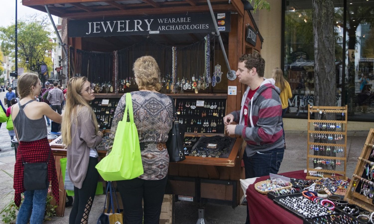UW-Madison PhD student Jacob Hellman attempts to sell jewelry to customers at his stand Wearable Archaeologies, a job he said “doesn’t feel like a job” because of his love for it.