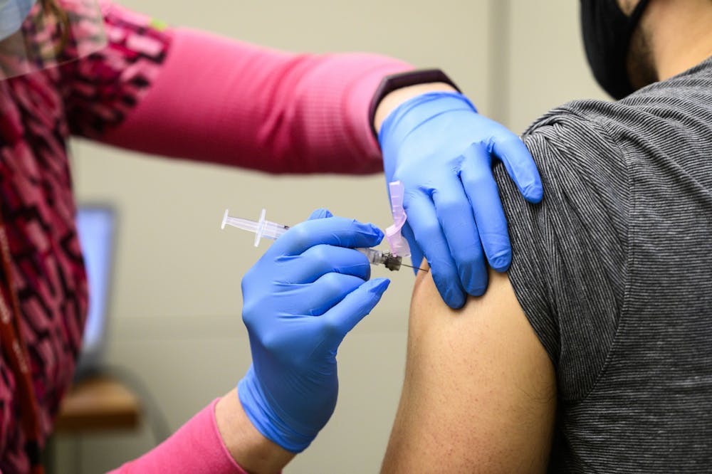 A nurse vaccinates an eligible Phase 1a recipient with the first of a two-dose shot of the Moderna COVID-19 vaccine &nbsp;