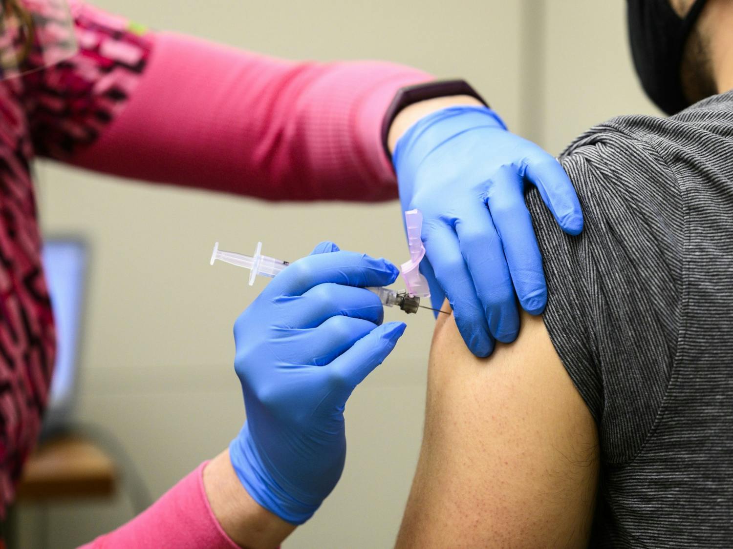 A nurse vaccinates an eligible Phase 1a recipient with the first of a two-dose shot of the Moderna COVID-19 vaccine &nbsp;