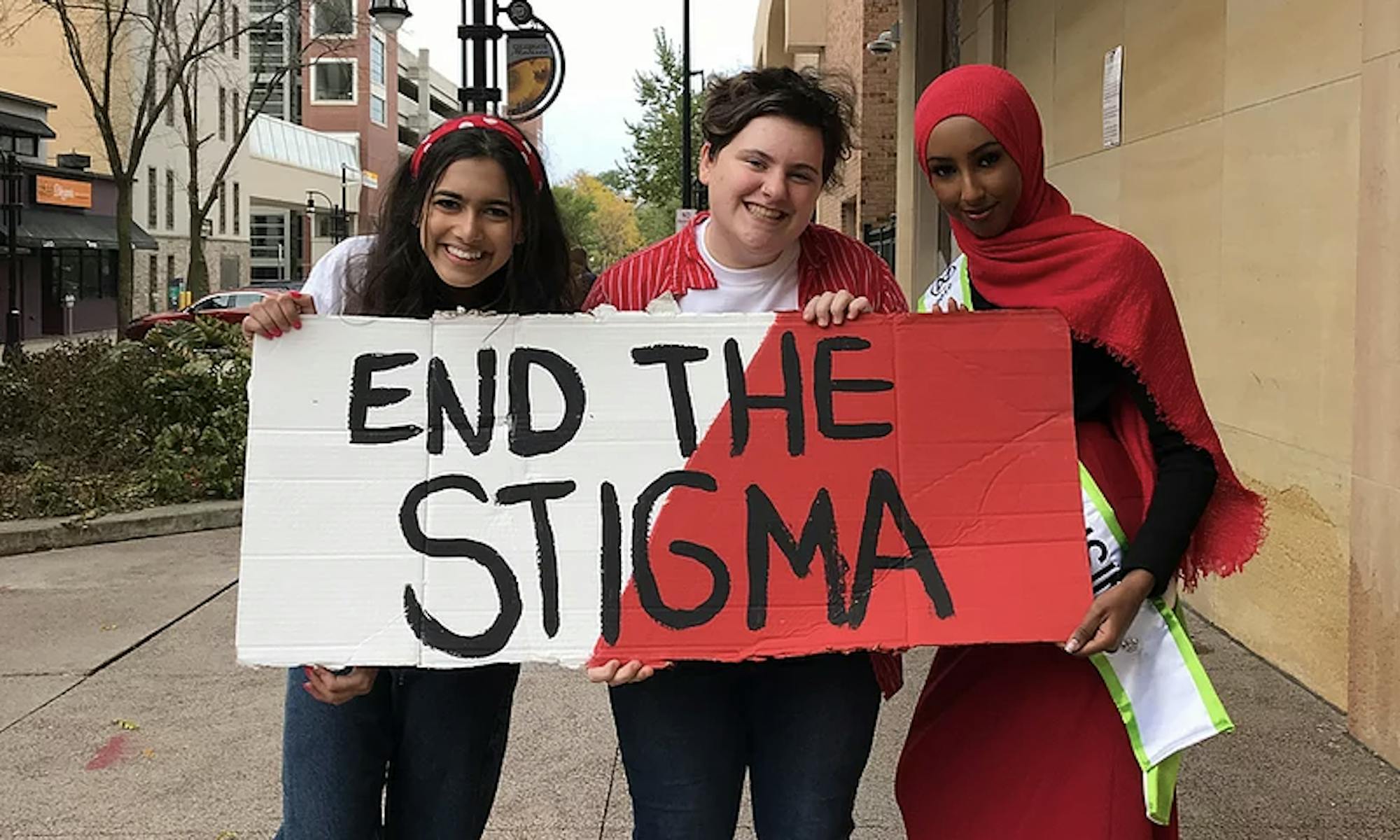 Photo of three people holding up a sign that says "END THE STIGMA"