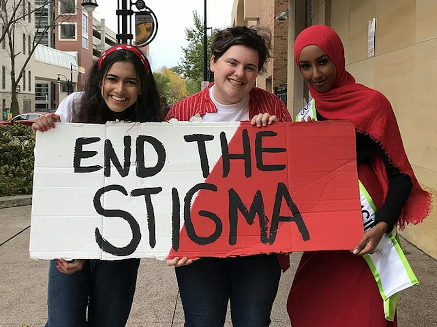 Photo of three people holding up a sign that says "END THE STIGMA"