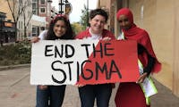 Photo of three people holding up a sign that says "END THE STIGMA"