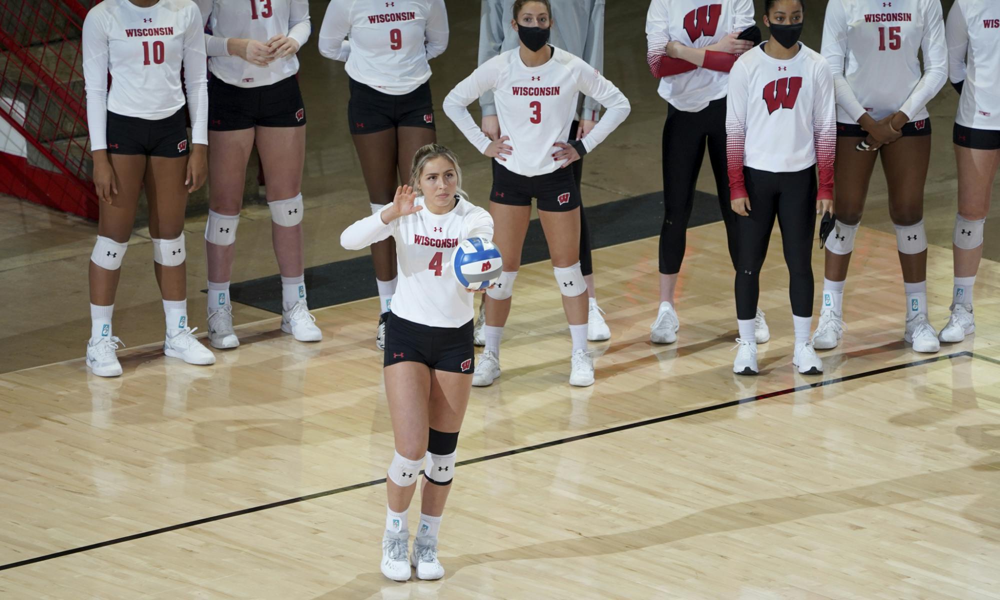 A Badger volleyball player getting ready to serve the ball.